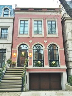 a red brick house with stairs leading up to the front door and two story windows