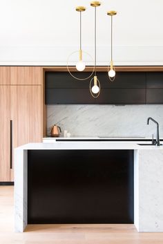 an island in the middle of a kitchen with marble counter tops and black cabinetry