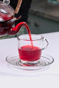 a red liquid being poured into a glass cup