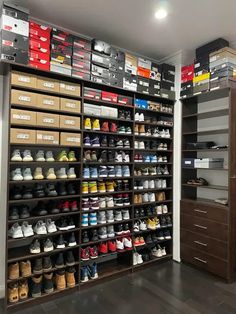 a large shoe rack with many pairs of shoes on it in a room filled with boxes and drawers