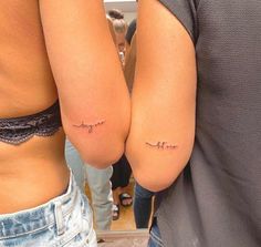 two people with small tattoos on their butts, one is holding the other's arm