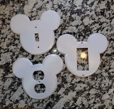 three mickey mouse light switch plates on a granite counter top with one facing the camera