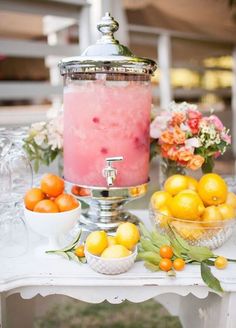 a table topped with lots of lemons next to a tall glass vase filled with water