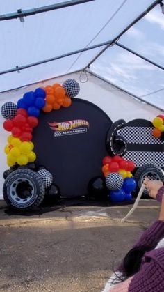 a woman standing in front of a car with balloons attached to it's side