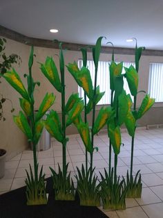 some green plants are sitting in the middle of a tiled floored area with white tiles