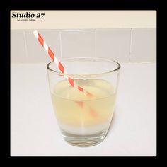 a glass filled with liquid next to a red and white striped straw on top of a counter