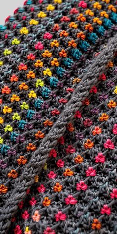 a crocheted blanket with multicolored flowers on it's edges, folded up