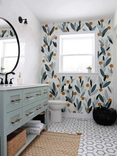 a bathroom with a toilet, sink and wallpaper in blue and yellow colors on the walls