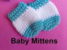 two crocheted mittens sitting on top of a pink surface with the words baby mittens written below them