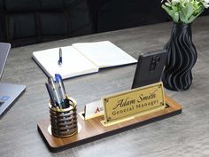 a desk with a pen holder, cell phone and laptop on it