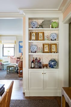 a white bookcase with blue and white plates on it in a living room area