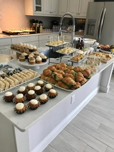 an assortment of pastries and desserts on display at a buffet table in a kitchen