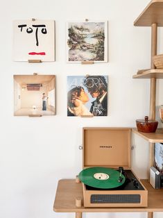 a record player sitting on top of a wooden table next to a wall covered in pictures