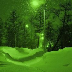 snow covered street lights and trees in the background at night with green hued sky