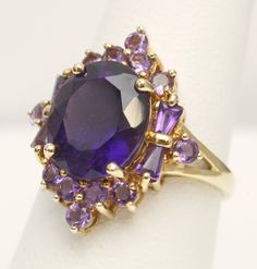 Signed Heng Ngai Amethyst Cluster Cocktail Ring 14K Yellow Gold US Size 7 Weight: 4.3 grams Center Amethyst measures approx. 12mm x 10mm Head of Ring measures approx.  21.6mm x 18.9mm This is a pre-owned item in Good Condition. It does show signs of use/wear but there is still lots of life left to this ring. Please note: Monitors/cellphone screens are not all calibrated the same, so colors of stones may appear different in person. CAT E 23-92101 Jewelry 2024, Amethyst Cocktail Ring, Prom Outfit, Gold Sign, Heart Necklace Diamond, Amethyst Gem, Purple Band, Amethyst Cluster, Amethyst Ring