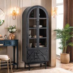 a tall black cabinet with glass doors in a living room next to a table and chair