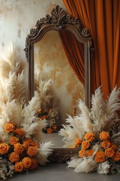 an ornate mirror with flowers and feathers in front of orange drapes on a wall