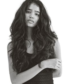 a black and white photo of a woman with long curly hair wearing a tank top