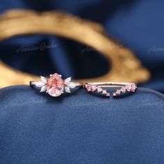 a pink diamond ring sitting on top of a blue bag