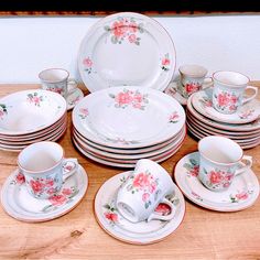 a table topped with lots of white and pink dishes covered in floral print cups and saucers