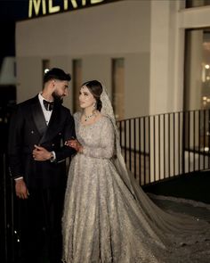 a bride and groom standing in front of a building at night with the words merry written on it