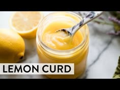 a glass jar filled with lemon curd next to two lemons