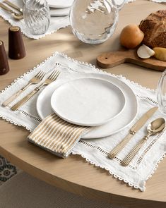 the table is set with white plates and silverware, along with bread on it