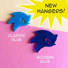 two blue and one pink plastic animal heads on top of a cardboard box that says new hangers classic blue modern blue