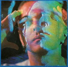 a man with his hands on his head while he is covered in colored paint and looking at the camera