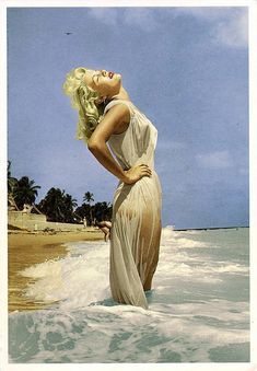 a woman is standing in the water at the beach