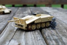 two toy army vehicles sitting on top of a wooden table