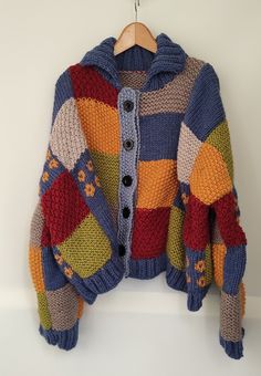 a multicolored cardigan sweater hanging on a hanger with a button down the middle