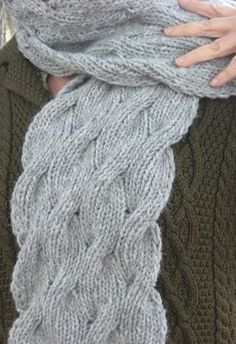 a woman wearing a gray knitted scarf with her hands on the back of her neck