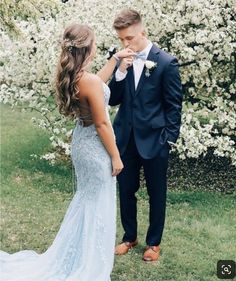 a bride and groom standing in front of white flowers