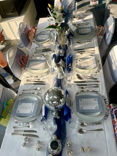 the table is set with silver and blue plates, silverware, and flower centerpieces