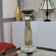 a glass table with a candle holder on it and a red chair in the background