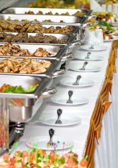 many trays of food are lined up on a buffet table