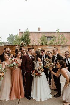 a group of people standing next to each other in front of a building with flowers