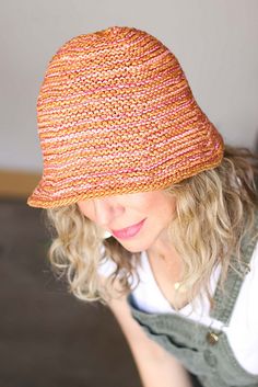 a woman with blonde hair wearing a knitted orange and pink hat on her head