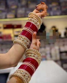 two hands are holding each other with bracelets and rings on their wrists in front of a store display