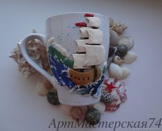 there is a coffee cup with a sailboat on it and sea shells around it