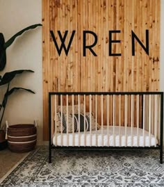 a baby crib in front of a wooden wall with the word wrenn written on it