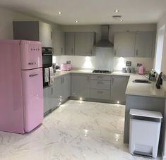 a pink refrigerator sitting in the middle of a kitchen next to a stove top oven