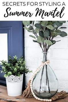 a vase filled with green plants on top of a wooden table next to a potted plant