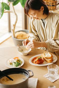 a woman sitting at a table eating food with chopsticks in her hand,