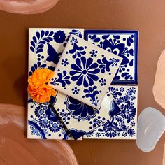 two blue and white plates with an orange flower on them, sitting next to each other