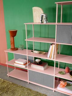 a pink shelf with books and vases on it