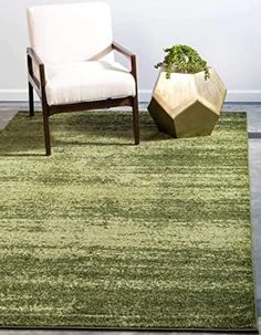 a green rug with a chair and plant in it