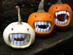 three pumpkins with teeth and fangs on them