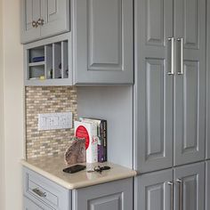 a kitchen with gray cabinets and marble counter tops in the center, along with a book shelf